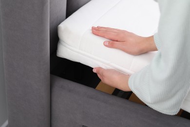 Woman putting new soft mattress on bed, closeup