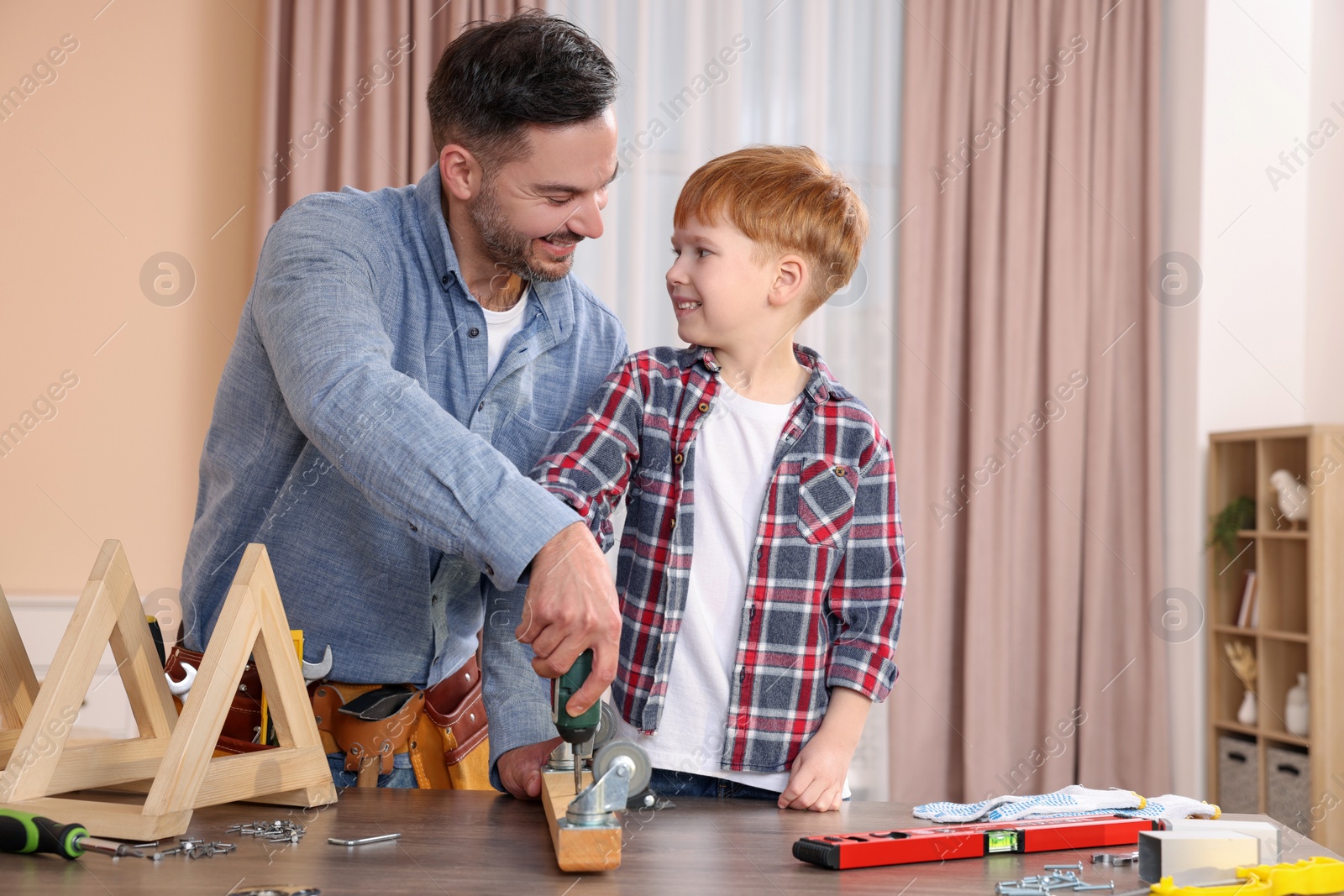 Photo of Father and son screwing wooden plank at home. Repair work