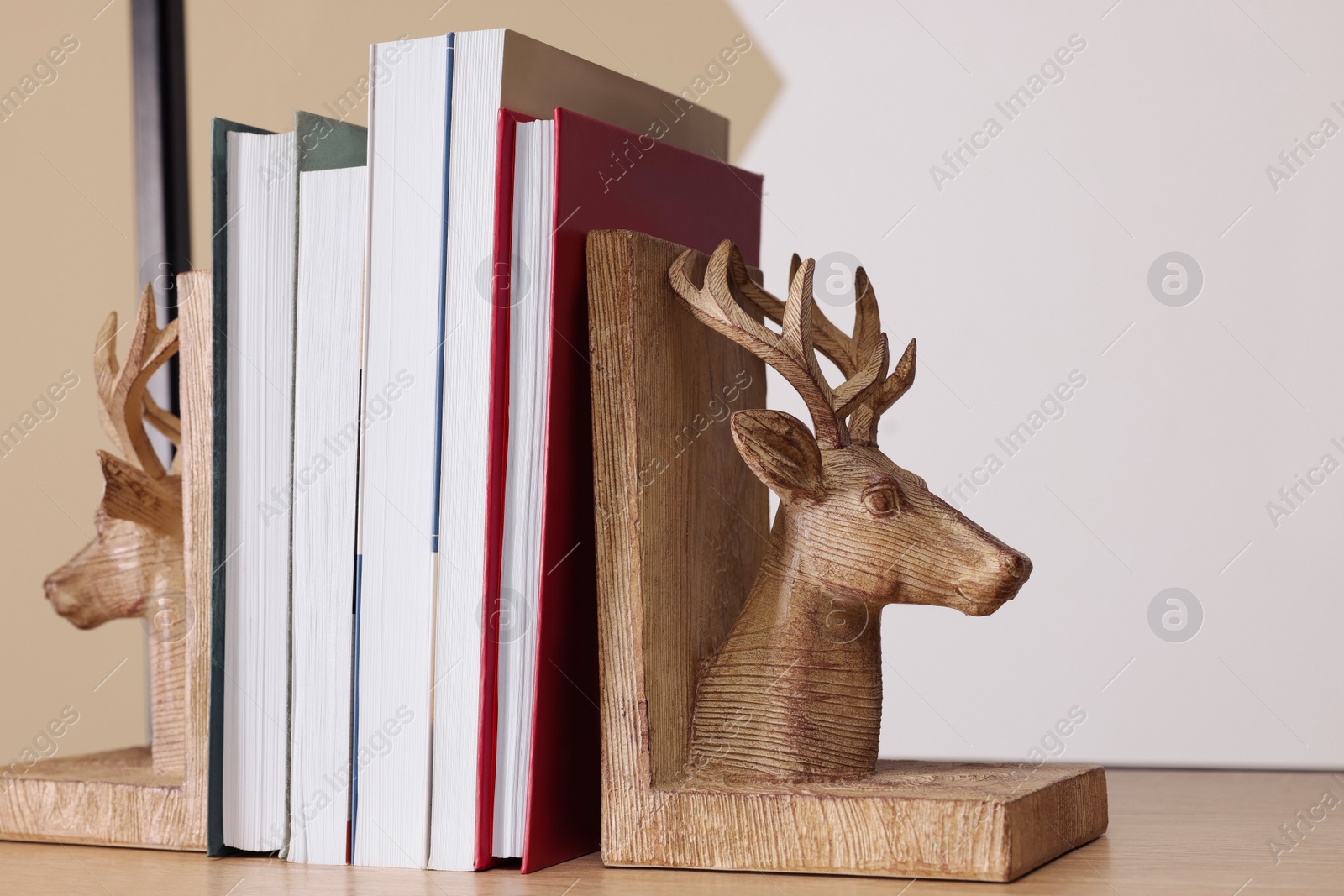 Photo of Wooden deer shaped bookends with books on shelf indoors