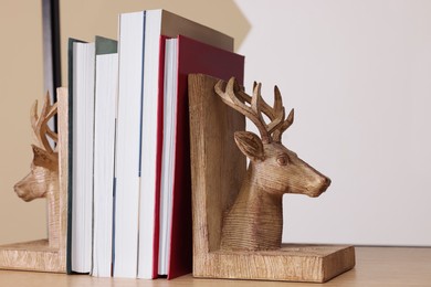 Photo of Wooden deer shaped bookends with books on shelf indoors