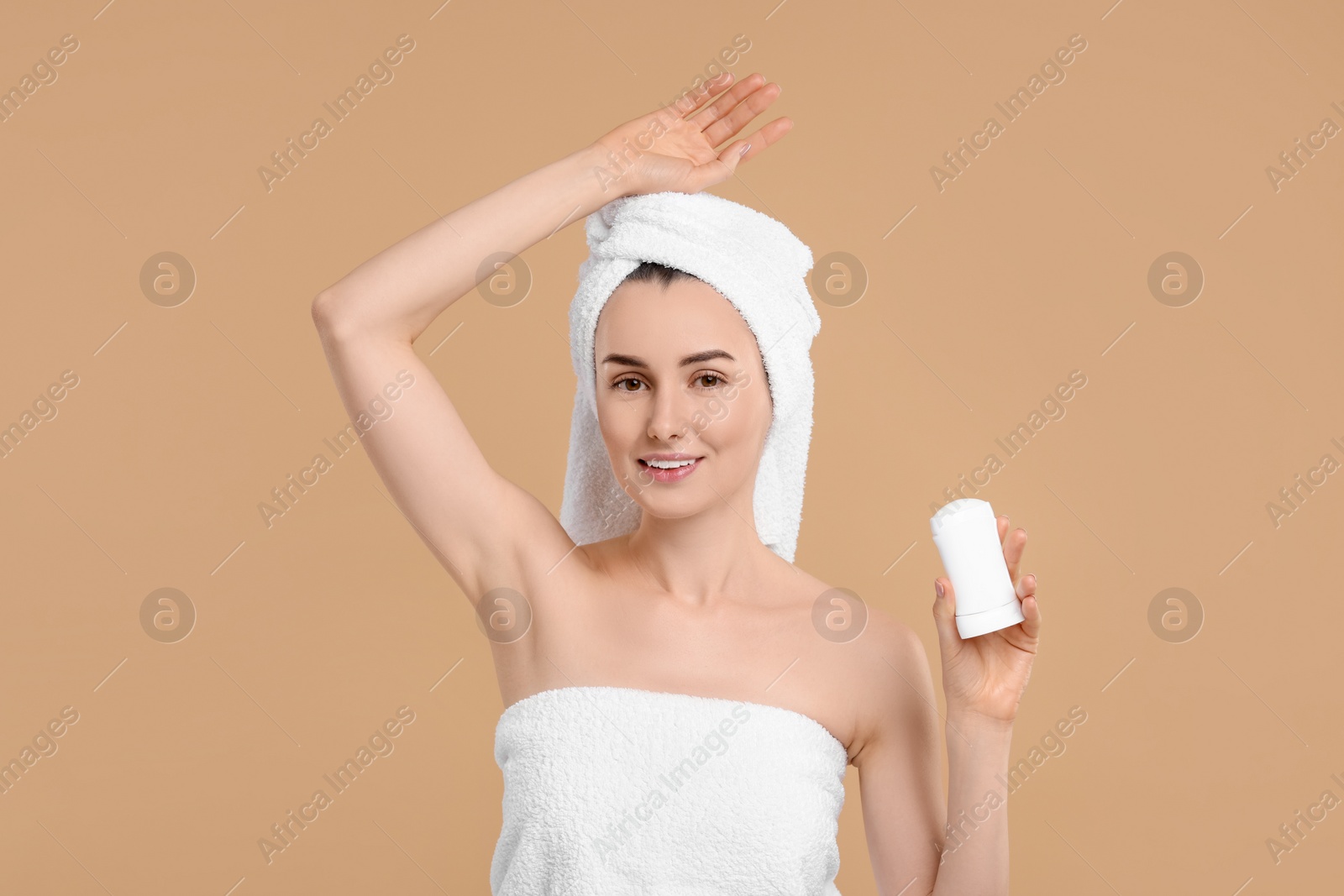 Photo of Beautiful woman applying deodorant on beige background