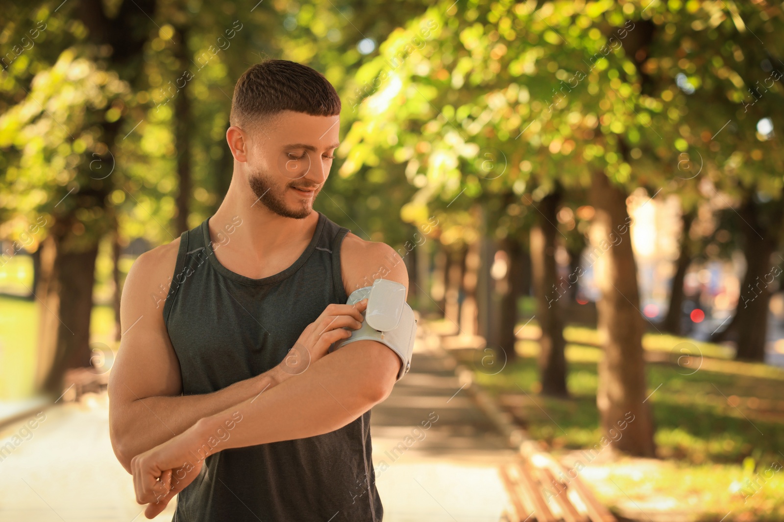 Photo of Attractive man checking blood pressure with modern monitor after training in park. Space for text