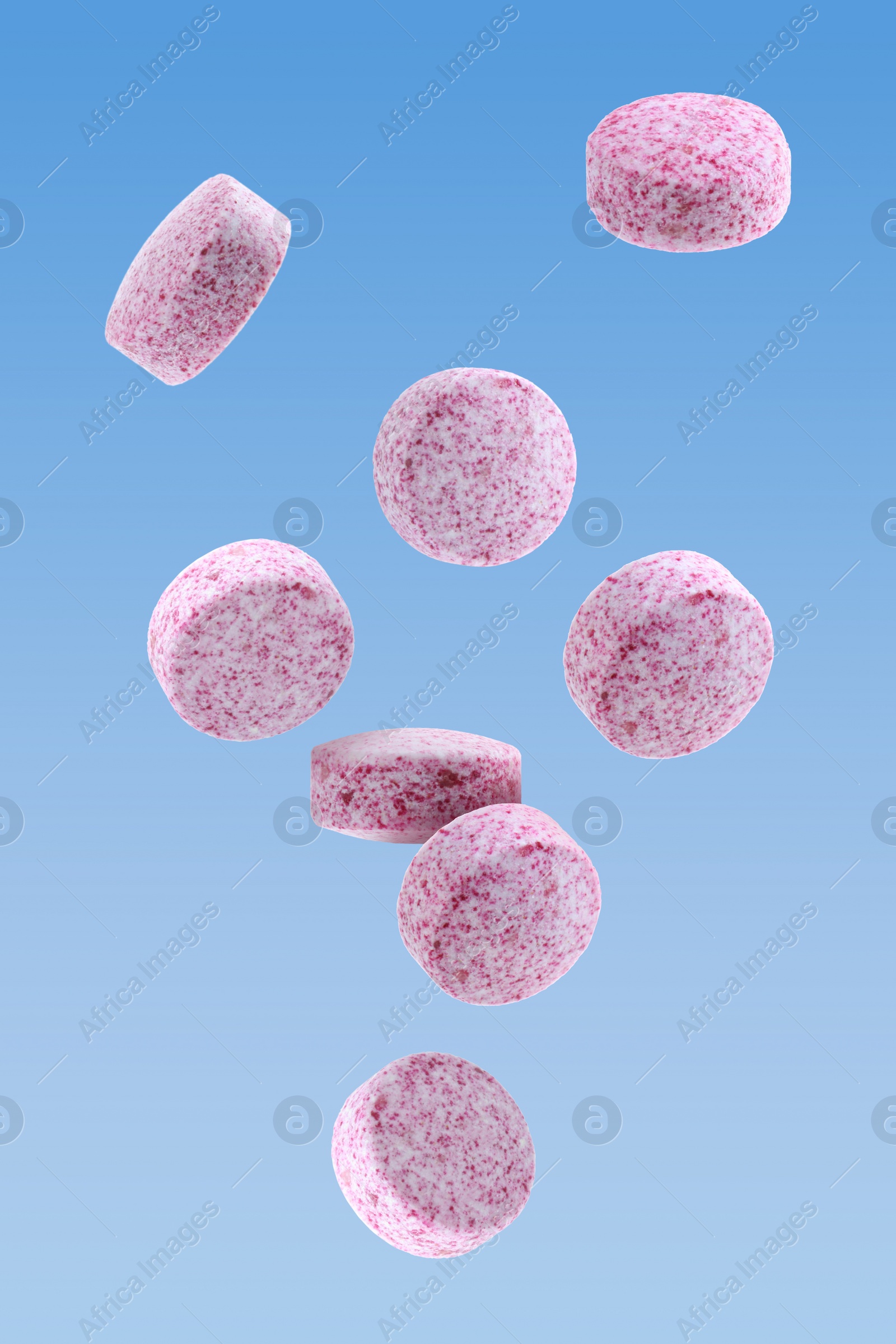 Image of Vitamin. Pink tablets falling on light blue gradient background