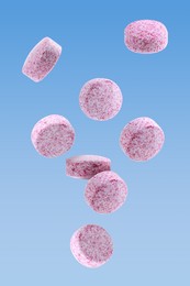 Image of Vitamin. Pink tablets falling on light blue gradient background