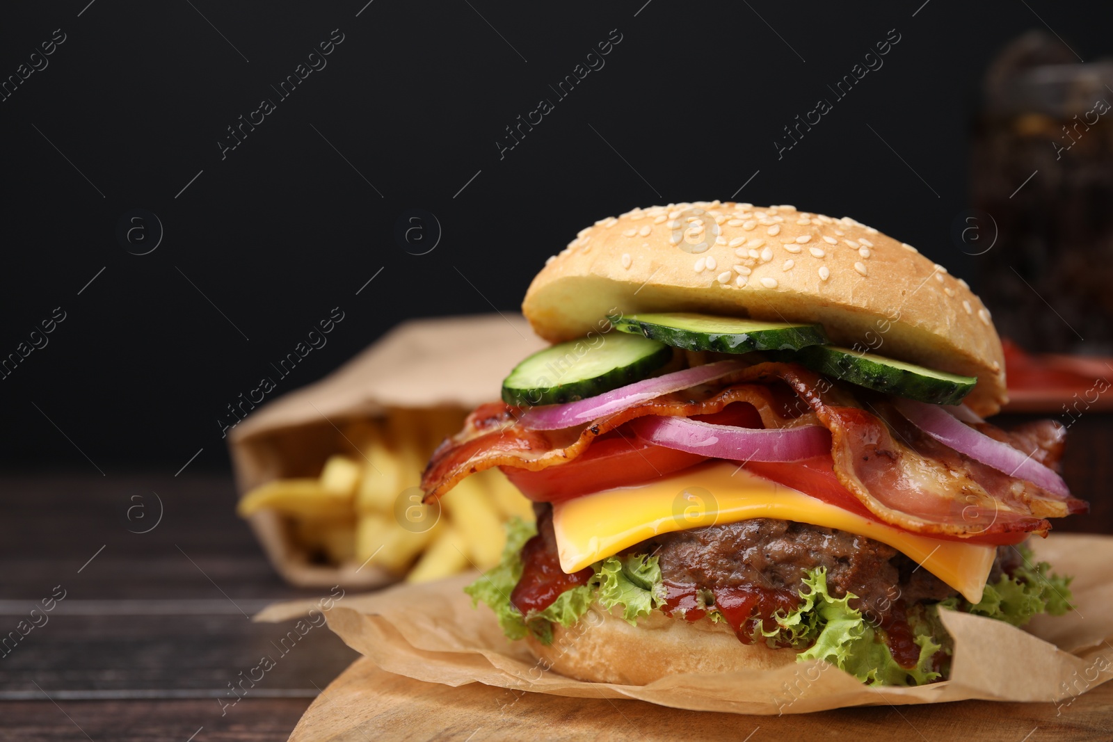 Photo of Tasty burger with bacon, vegetables and patty on wooden table, closeup. Space for text