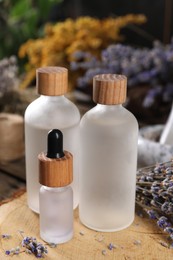 Photo of Bottles of essential oils and dry lavender flowers on wooden table, closeup. Medicinal herbs