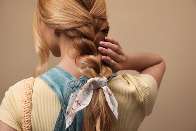 Young woman with stylish bandana on beige background, closeup