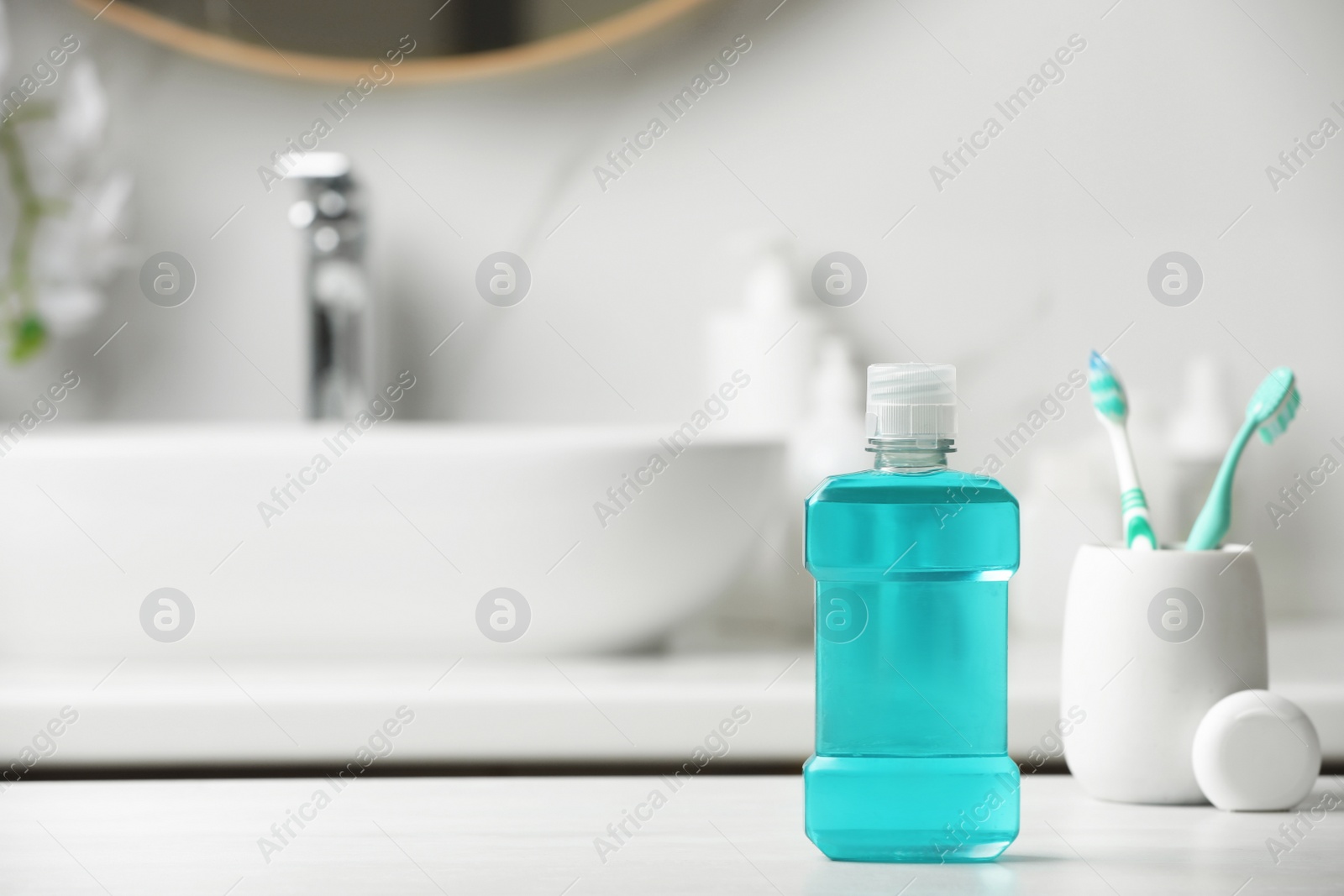 Photo of Mouthwash, toothbrushes and dental floss on white countertop in bathroom. Space for text