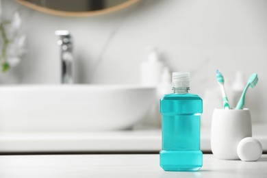 Photo of Mouthwash, toothbrushes and dental floss on white countertop in bathroom. Space for text
