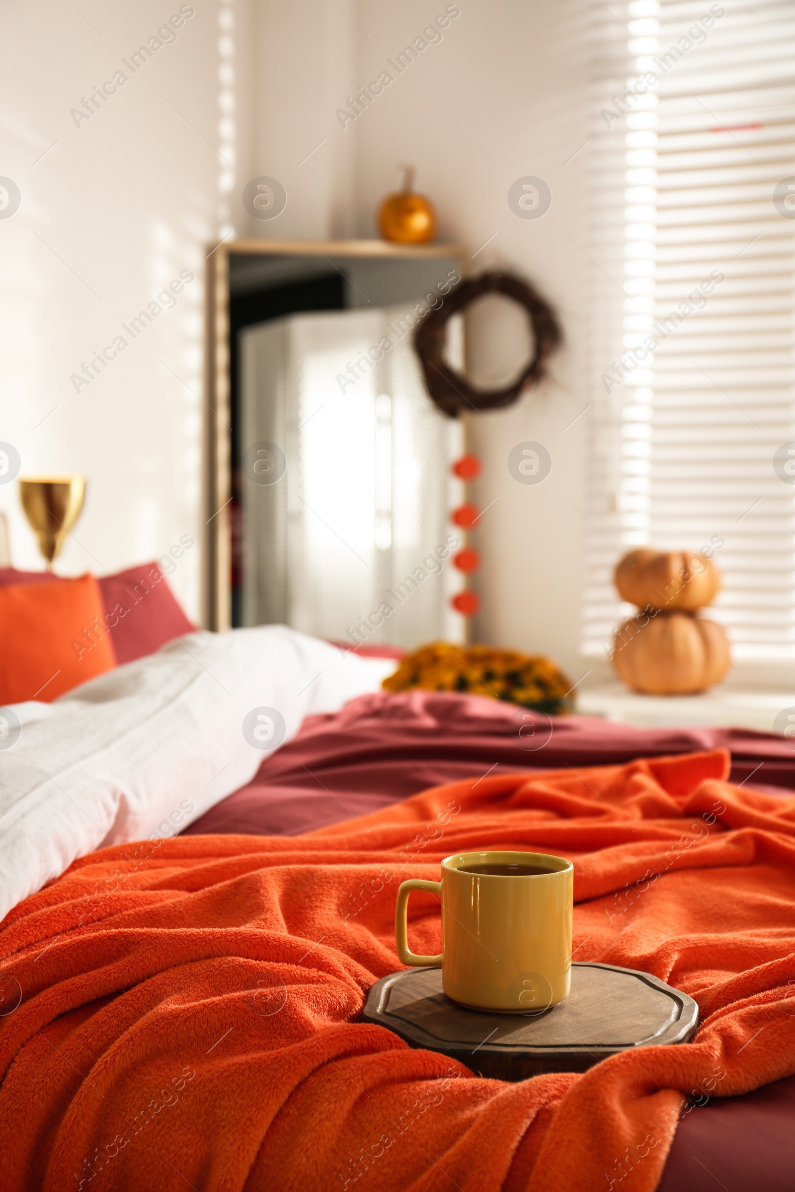 Photo of Hot drink on bed with orange blanket at home. Idea for decor in autumn colors