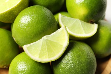 Photo of Whole and cut fresh limes on plate, closeup