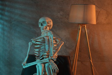 Photo of Waiting concept. Human skeleton sitting in armchair indoors