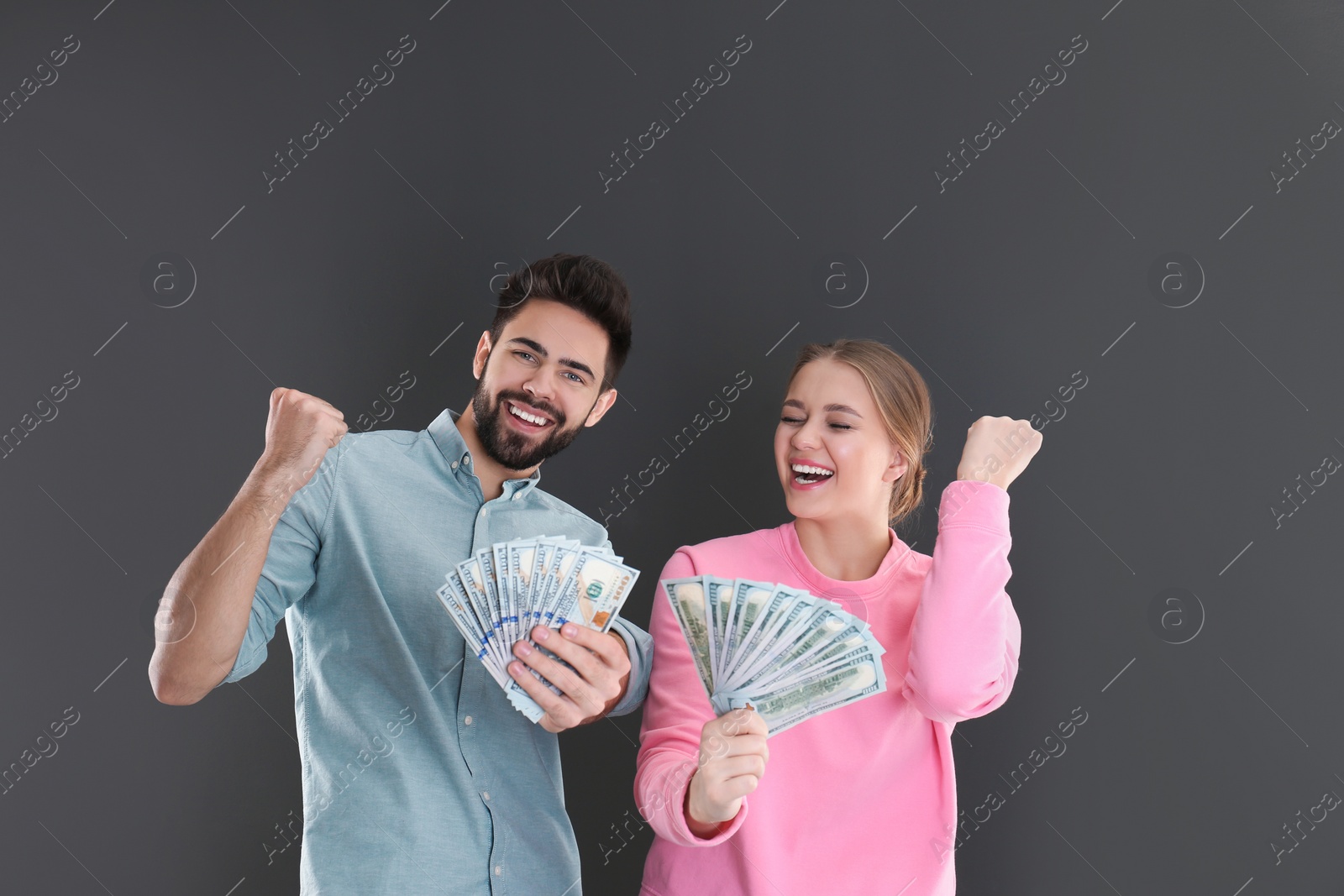 Photo of Happy young couple with money on grey background