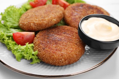 Photo of Delicious vegan cutlets, lettuce, tomato and sauce on white table, closeup