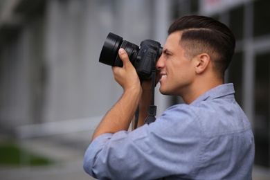 Photographer taking picture with professional camera on city street