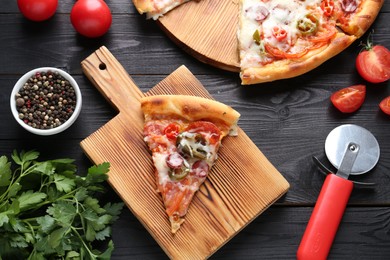 Delicious pizza Diablo, tomatoes, parsley, peppercorns and cutter on black wooden table, flat lay