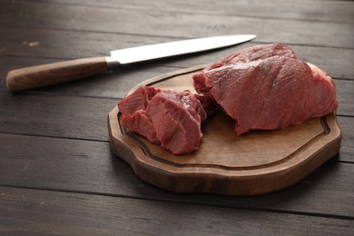 Photo of Pieces of raw beef meat and knife on wooden table