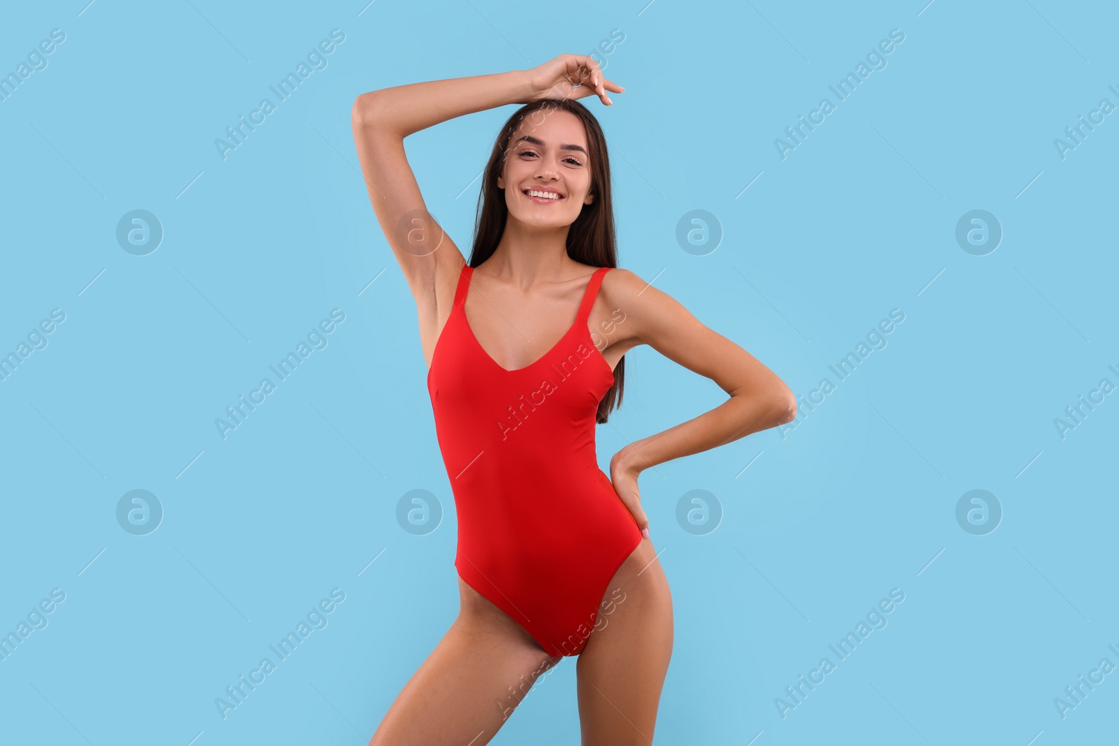 Photo of Young woman in stylish swimsuit on light blue background