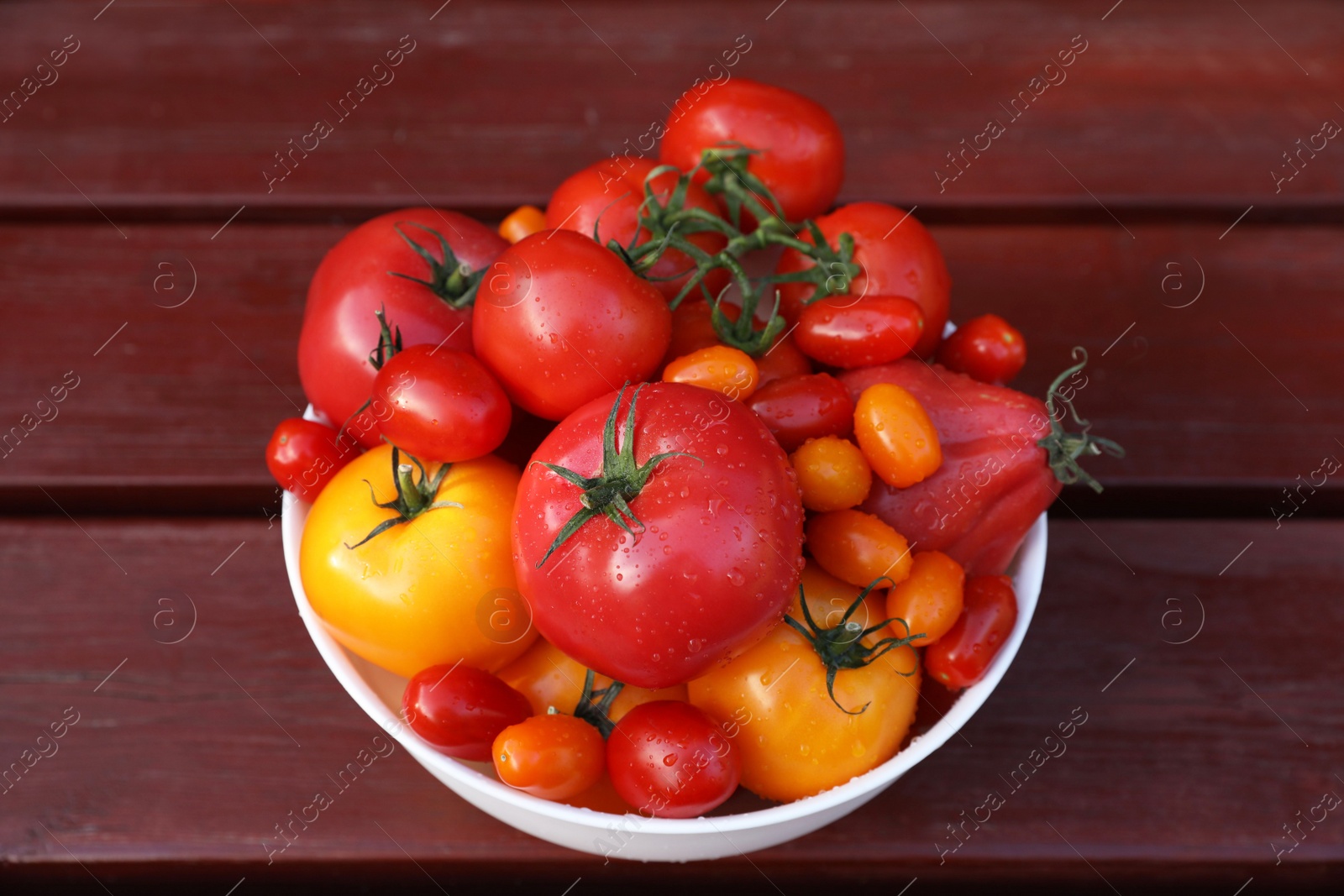 Photo of Bowl with fresh tomatoes on wooden table, top view