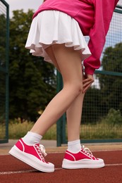 Photo of Woman wearing classic old school sneakers on sport court outdoors, closeup