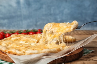 Taking tasty homemade pizza slice with melted cheese on table