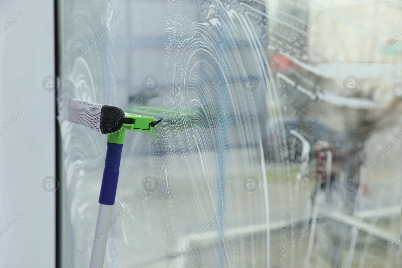 Photo of Cleaning window with squeegee indoors. Space for text