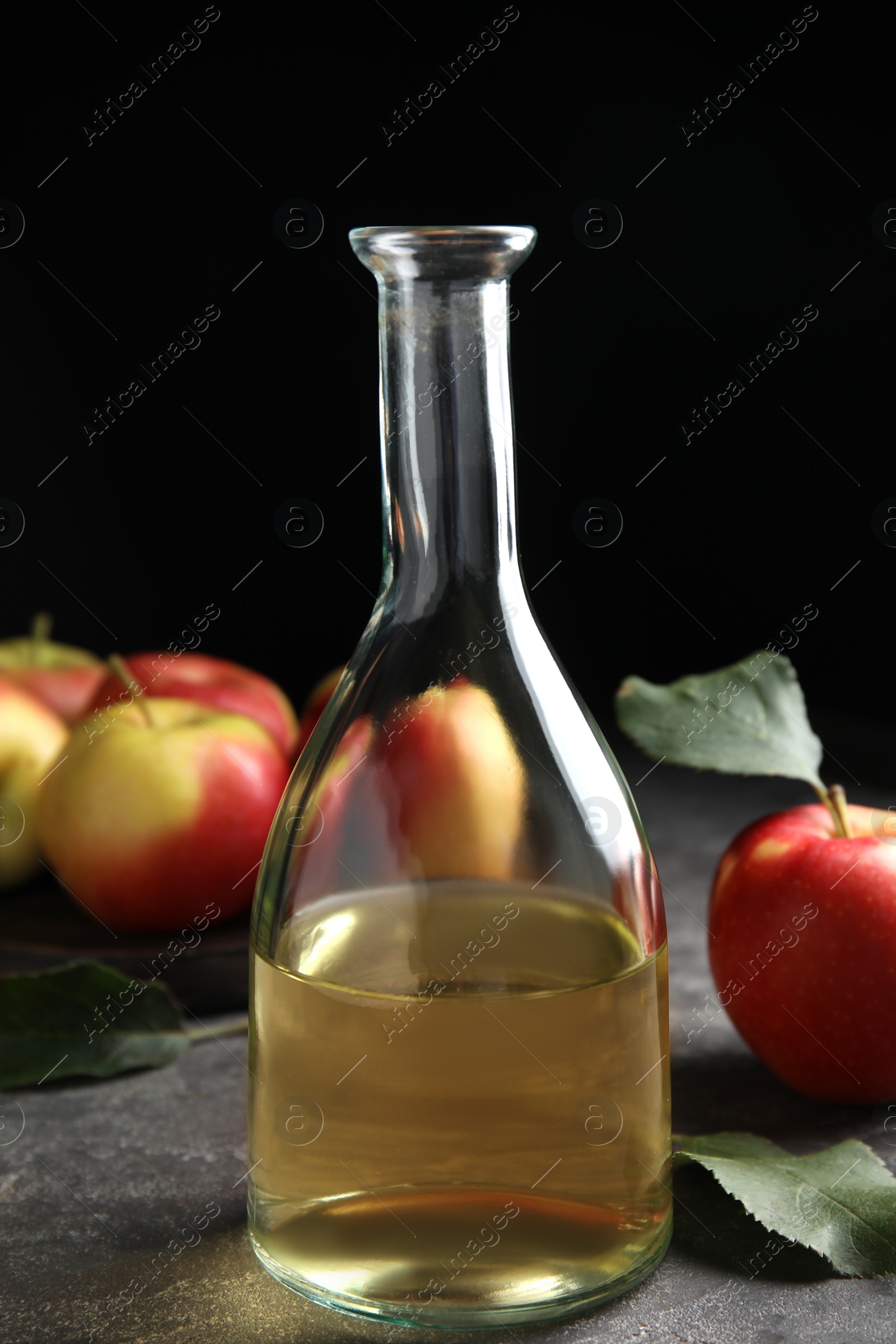 Photo of Natural apple vinegar and fresh fruits on grey table