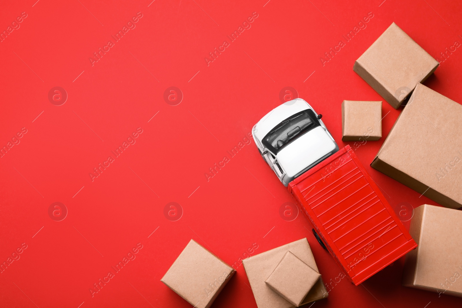 Photo of Top view of toy truck with boxes on red background. Logistics and wholesale concept