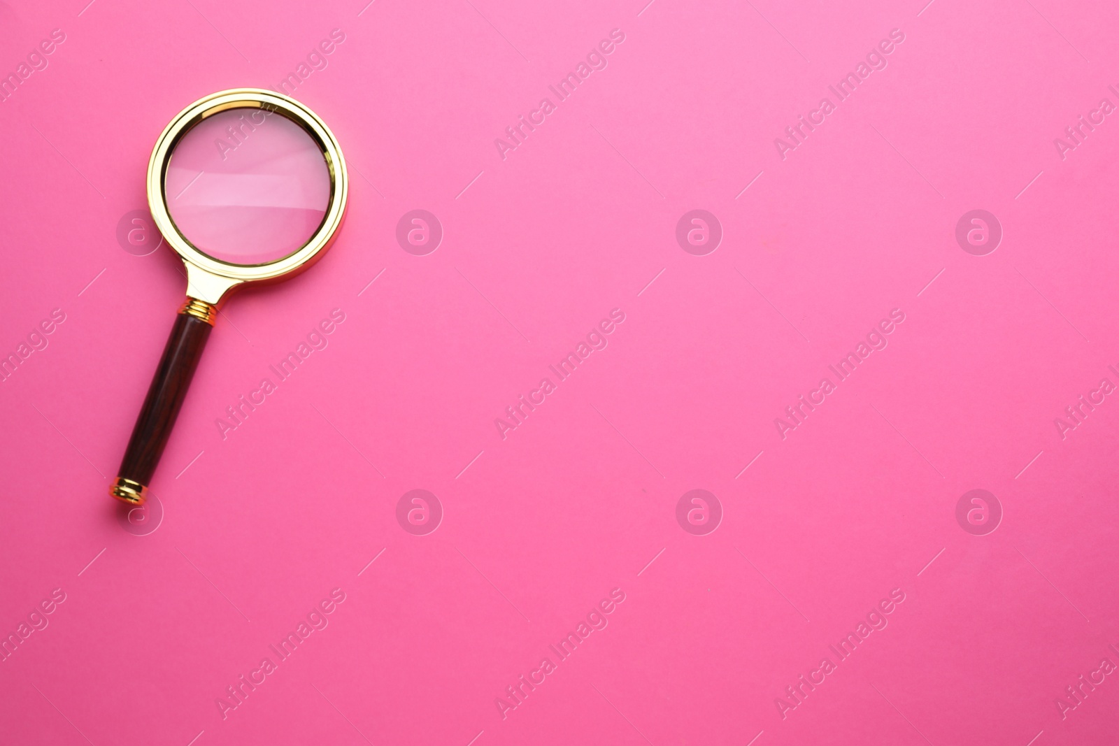Photo of Magnifying glass on pink background, top view. Space for text