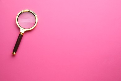 Magnifying glass on pink background, top view. Space for text