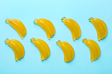 Delicious gummy banana candies on light blue background, flat lay