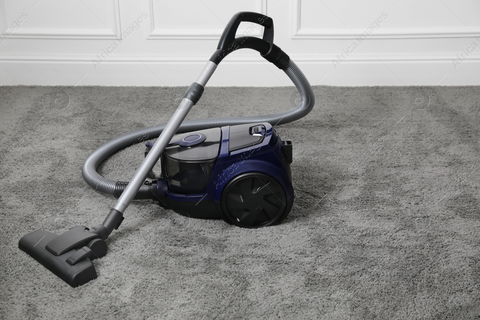 Photo of Modern black vacuum cleaner on carpet indoors