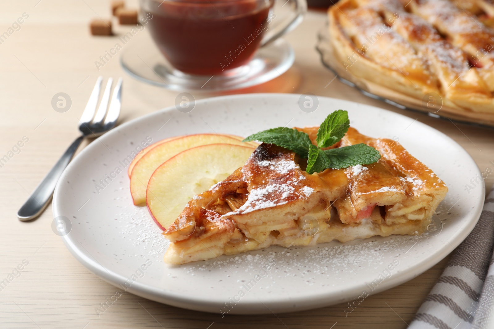 Photo of Slice of traditional apple pie served on wooden table, closeup