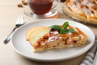 Slice of traditional apple pie served on wooden table, closeup