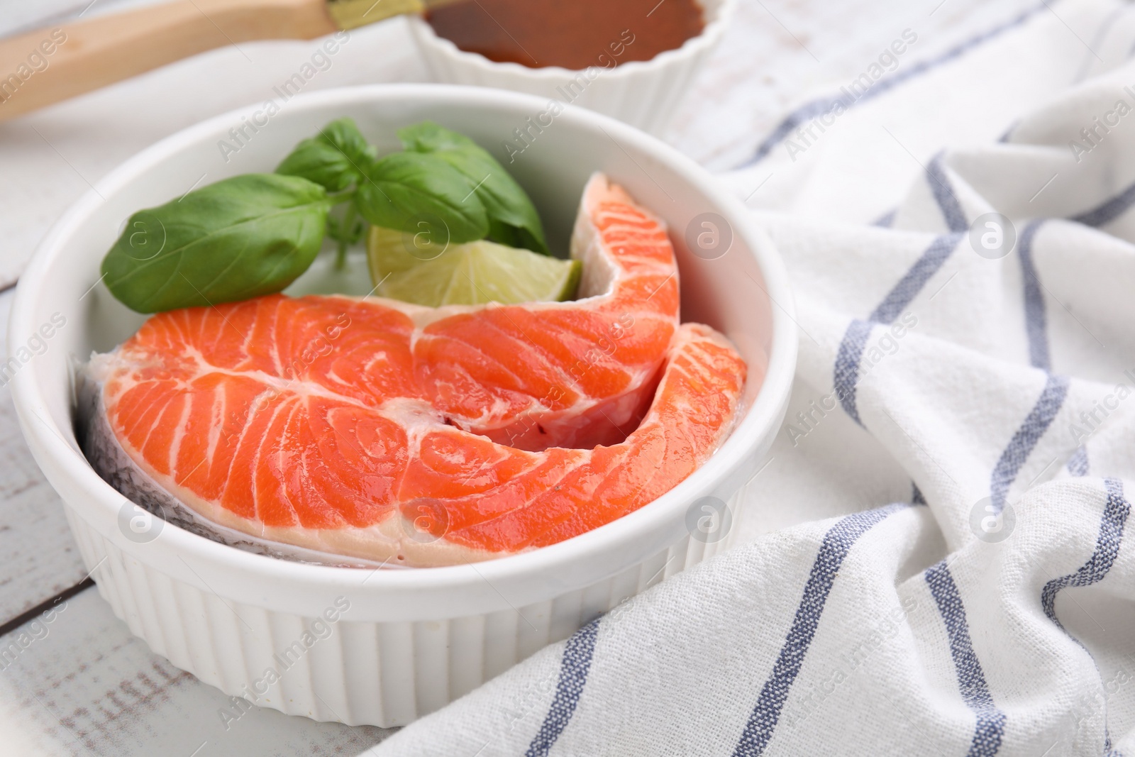 Photo of Fresh marinated fish and lime on white wooden table, closeup