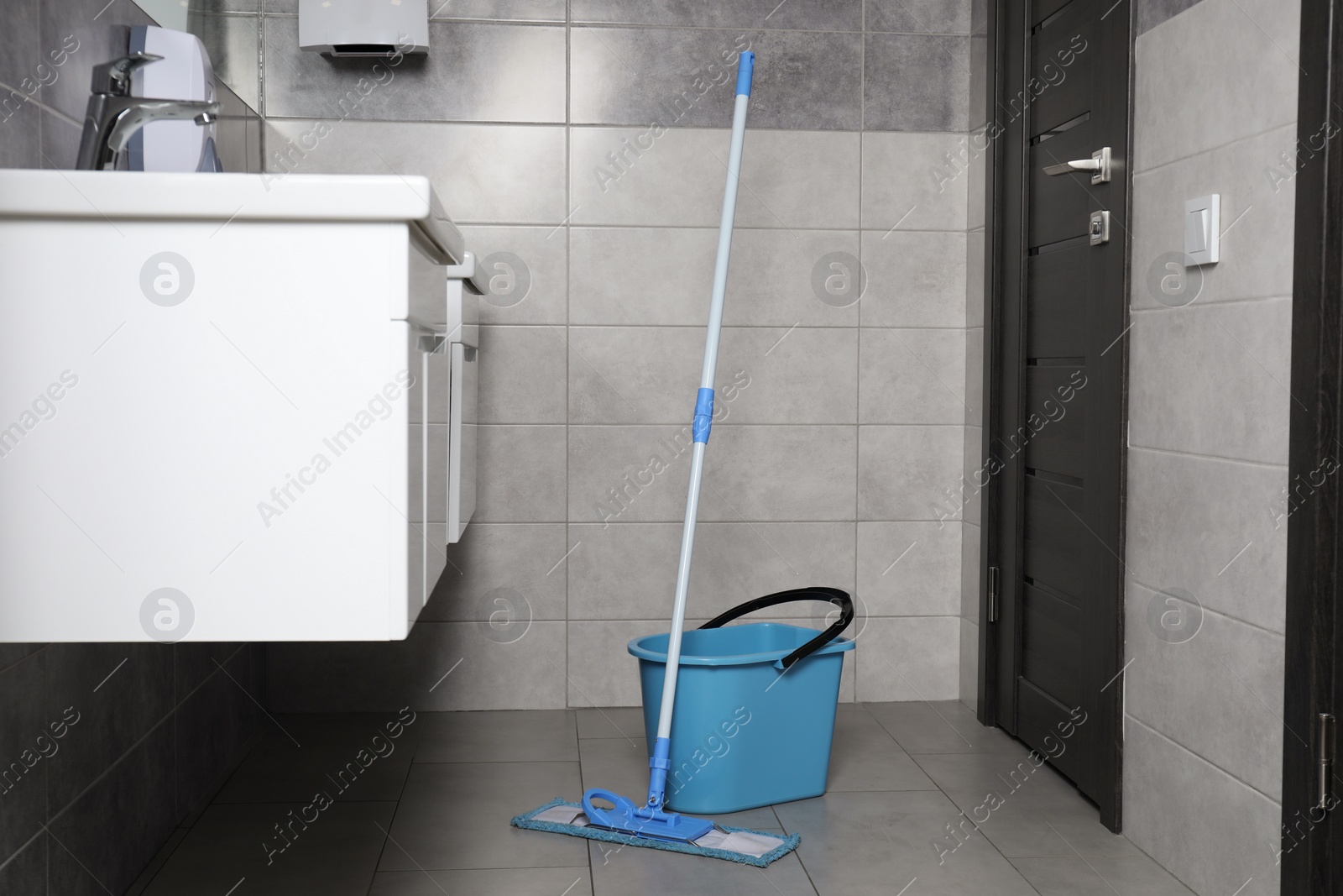 Photo of Mop and bucket near sinks in public toilet