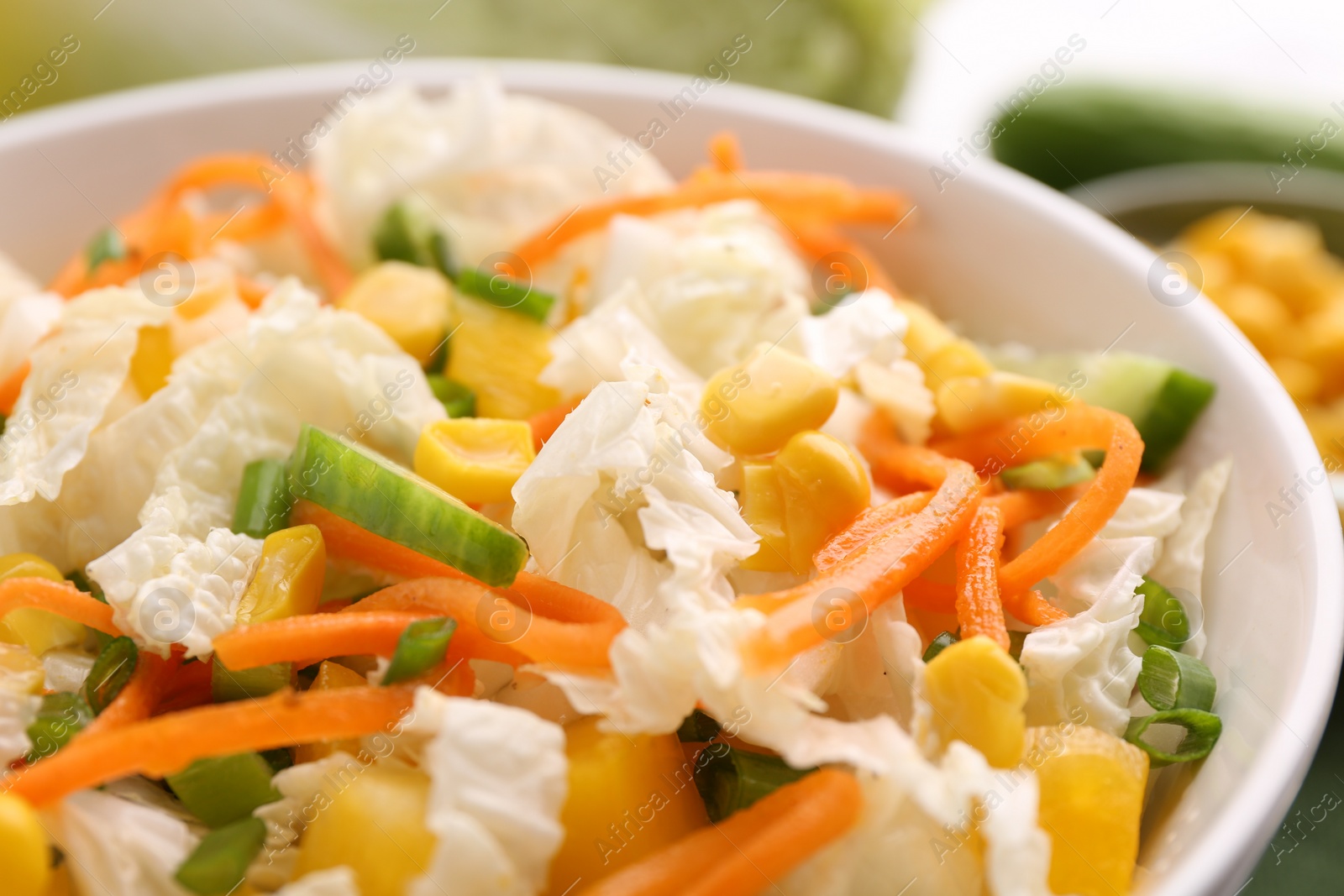 Photo of Tasty salad with Chinese cabbage, carrot, corn and cucumber in bowl on table, closeup