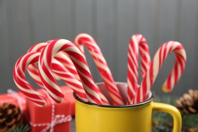 Photo of Many sweet candy canes in cup on grey background, closeup. Traditional Christmas treat