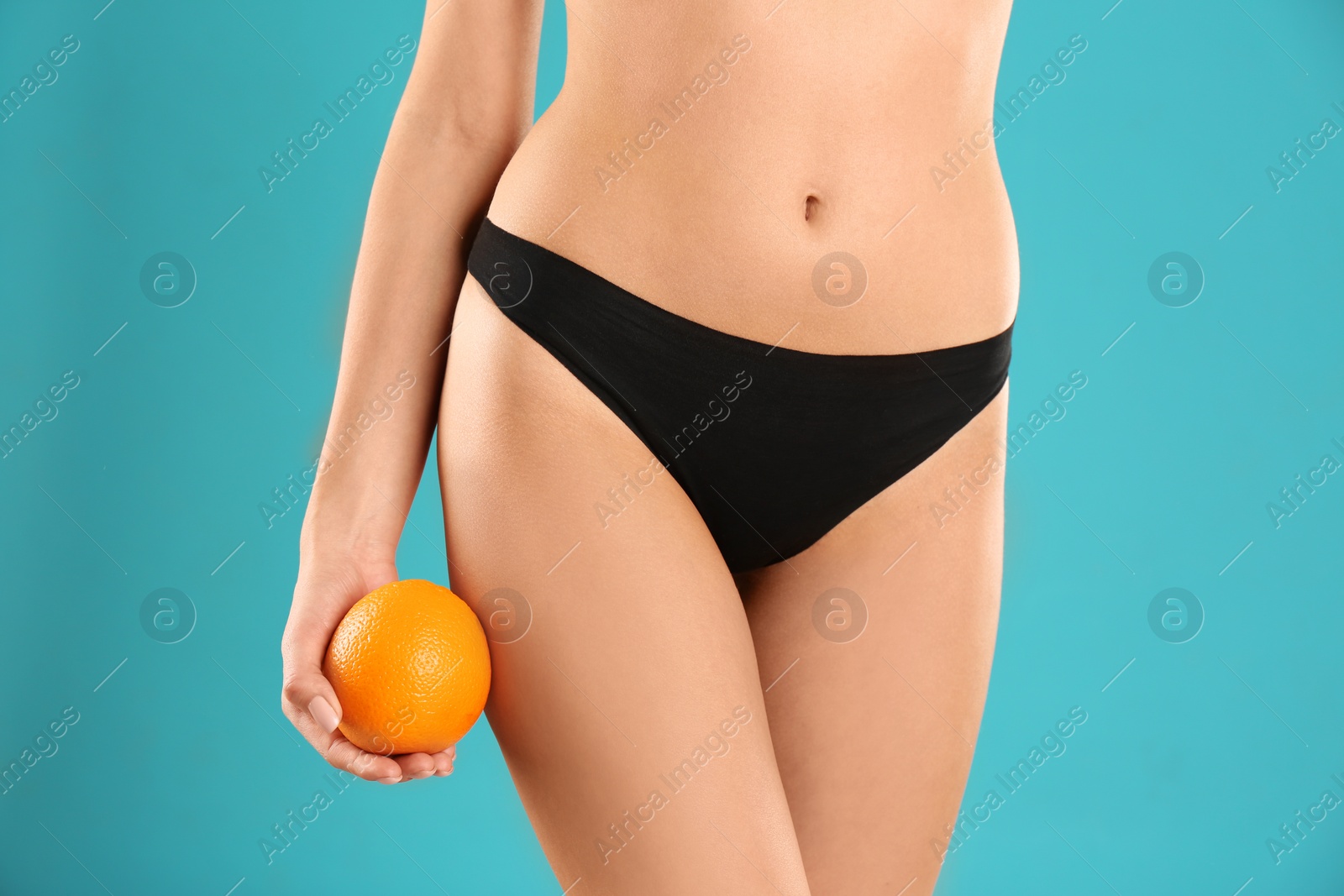 Photo of Closeup view of slim woman in underwear with orange on color background. Cellulite problem concept