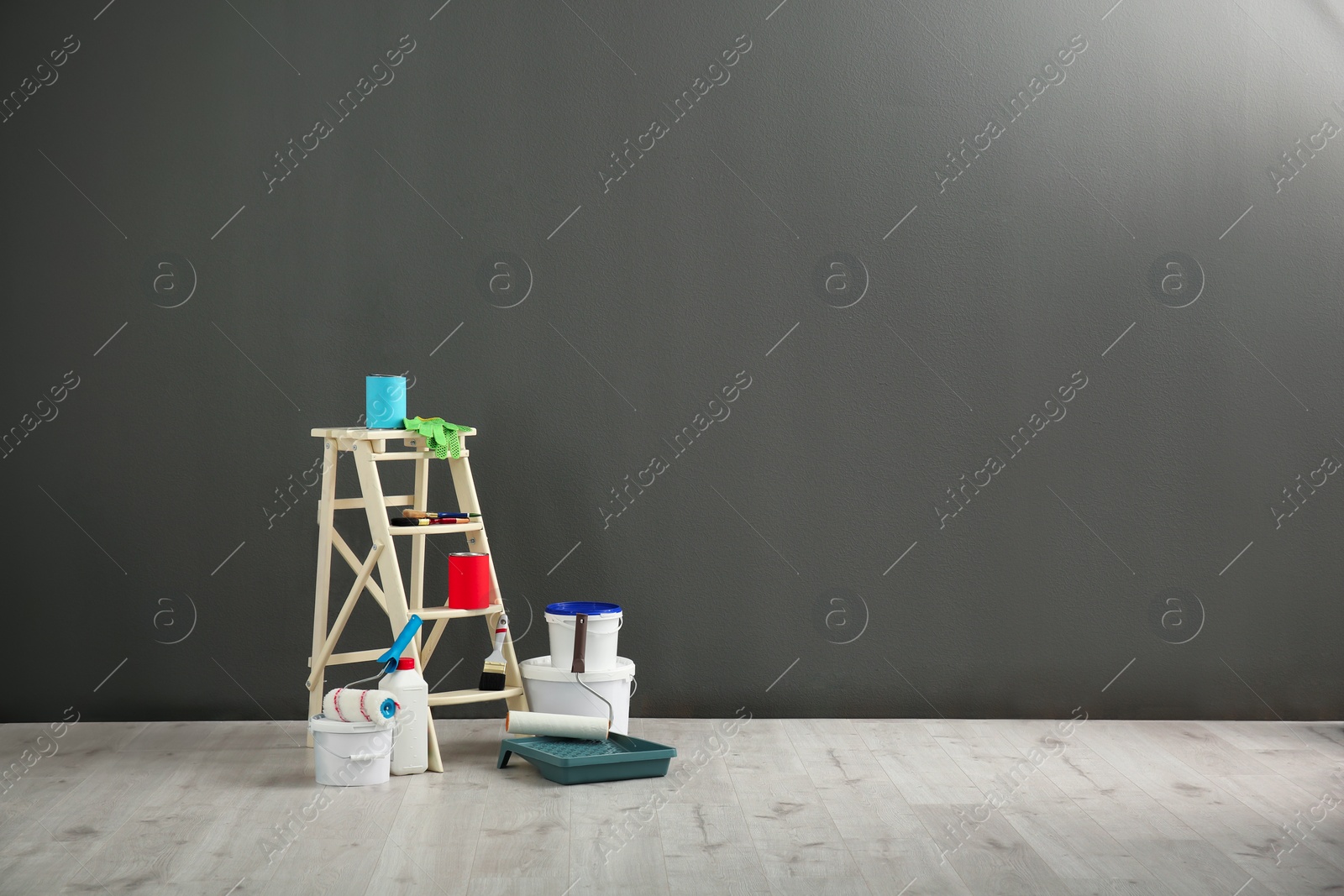 Photo of Step ladder and decorator's tools near grey wall