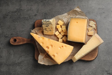 Different delicious cheeses served on grey table, top view