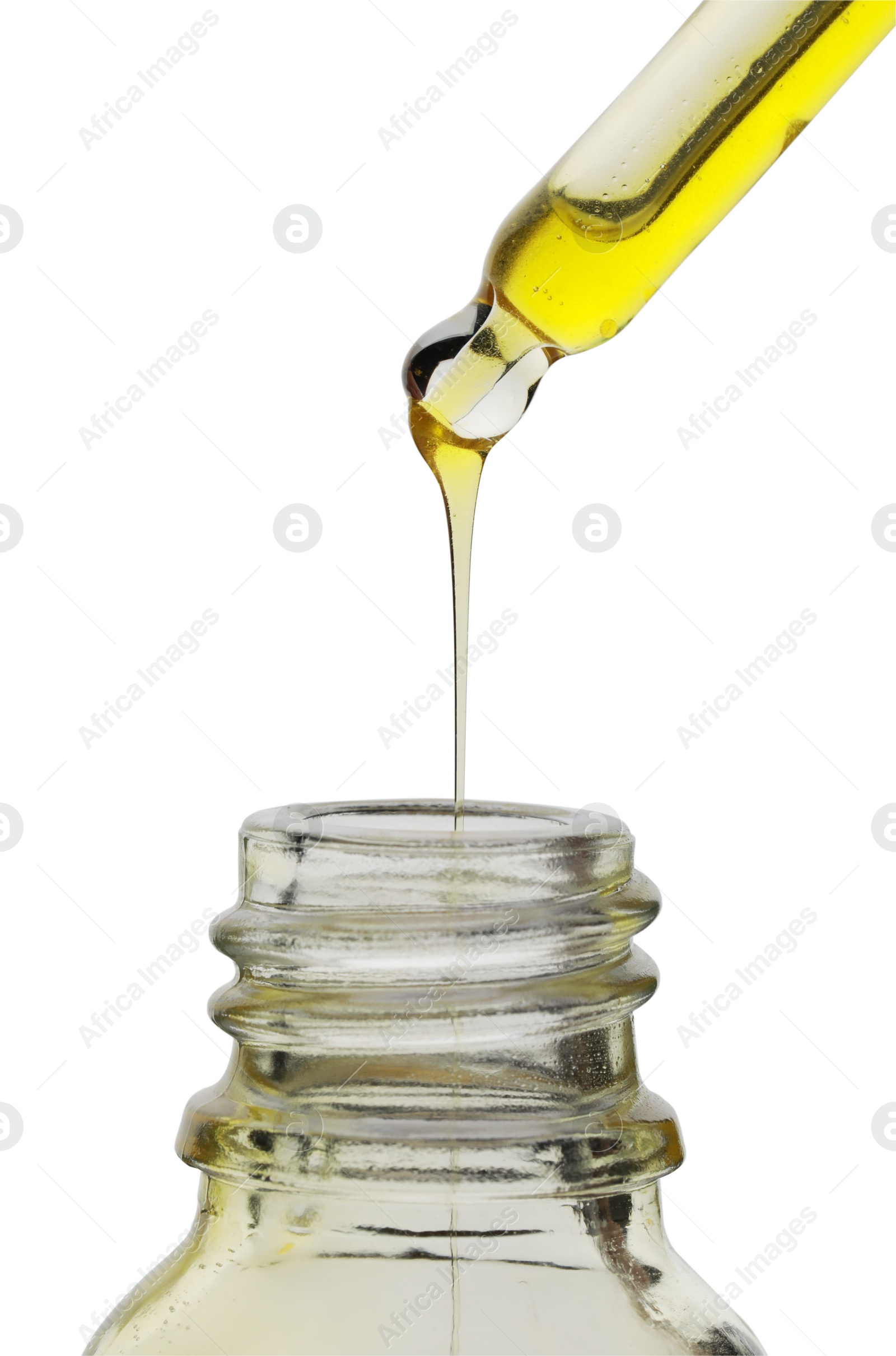 Photo of Dripping yellow facial serum from pipette into glass bottle on white background, closeup