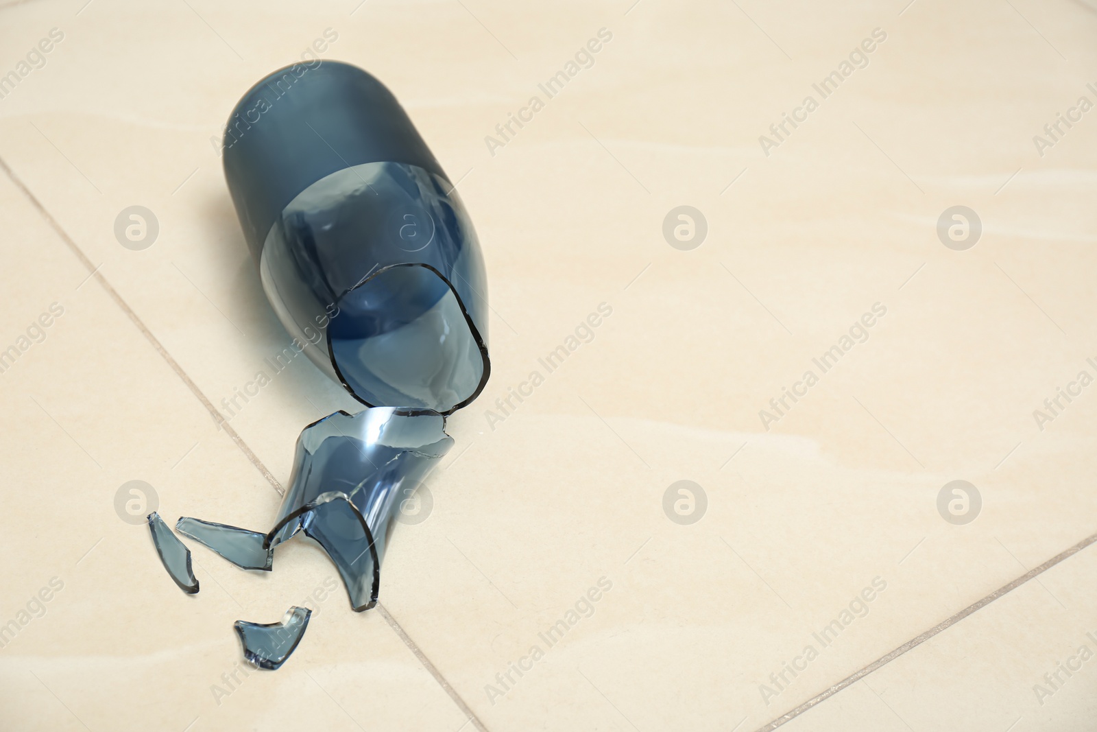 Photo of Broken blue glass vase on floor. Space for text