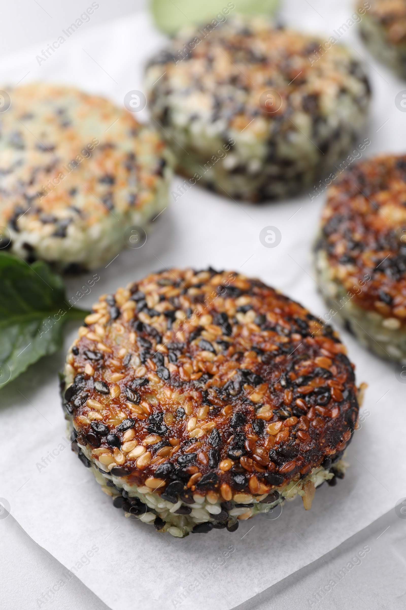 Photo of Delicious vegan cutlets with sesame on white table, closeup