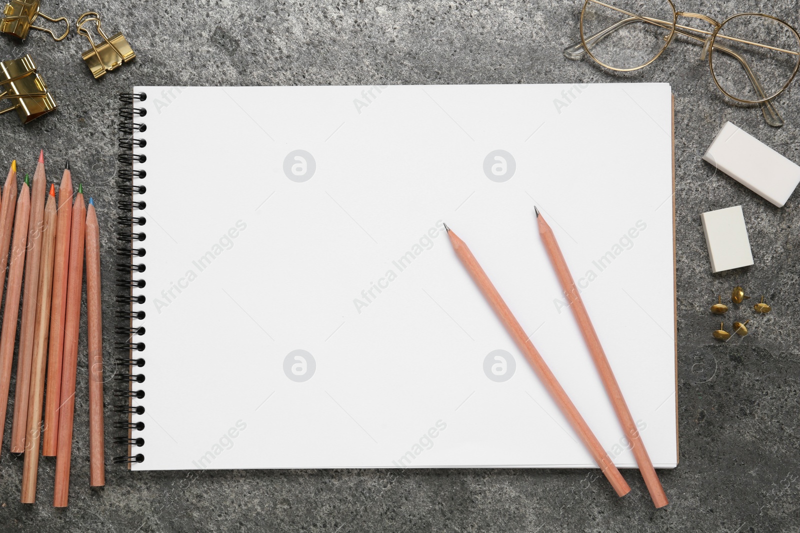 Photo of Flat lay composition with blank sketchbook on grey stone table. Space for text