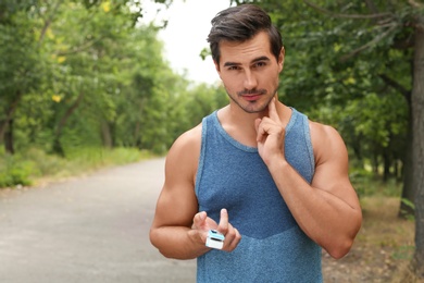 Young man checking pulse with medical device after training in park. Space for text