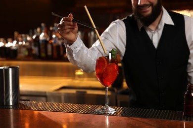 Photo of Bartender making fresh alcoholic cocktail at bar counter, closeup. Space for text