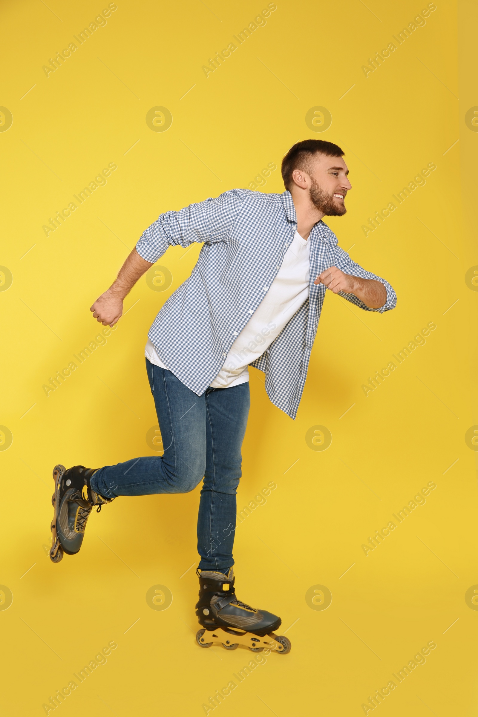 Photo of Young man with inline roller skates on color background