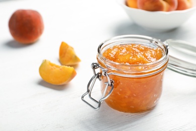 Photo of Jar with tasty peach jam on light table