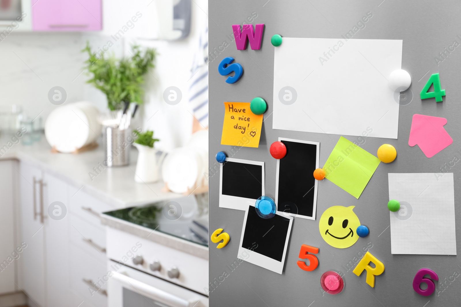 Photo of Sheets of paper and photos with colorful magnets on refrigerator door in kitchen. Space for text